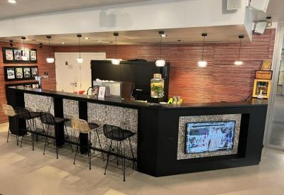 Sleek black reception desk and bar area with hanging lights and wood paneling.