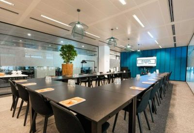 Boardroom with a U-shaped table, blue feature wall, and hanging pendant lights.