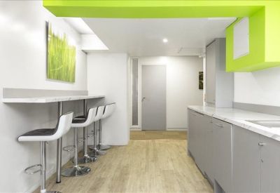 Modern office kitchen and breakout area with high stools and vibrant lime green accents.