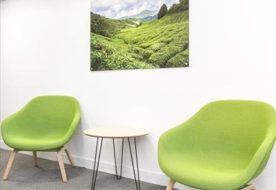 Bright breakout space featuring two lime green armchairs and a landscape wall art piece.