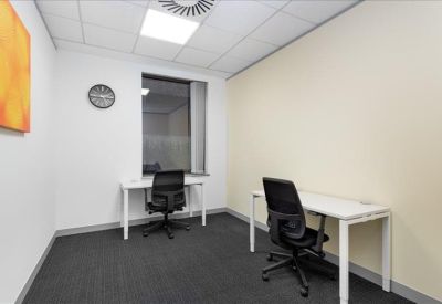 Bright two-person office suite with white desks and black mesh chairs.