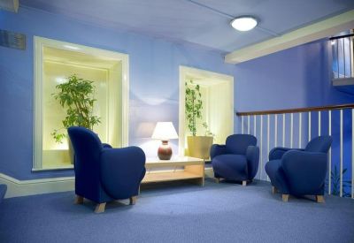 Comfortable lounge area with blue armchairs, potted plants, and soft ambient lighting.