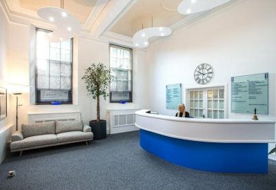Bright reception area with a curved blue and white desk, high ceilings, and modern light fixtures.
