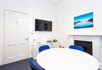 Four-person office suite with a round table and a bright blue accent wall.