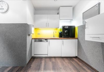 Compact kitchen area with coffee machine and bright yellow backsplash.