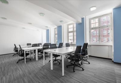 Open-plan workspace with rows of white desks and black chairs.