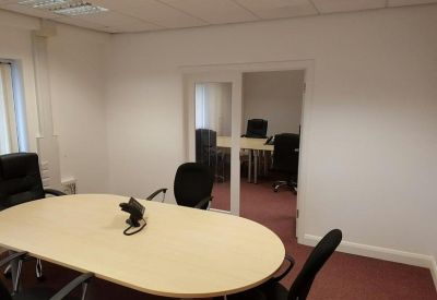 Bright meeting room featuring a blonde wood oval table and black office chairs.