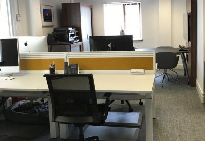 Modern workspace with white desks, yellow privacy screens, and grey carpeting.