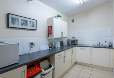 Communal kitchen area with white cabinetry, dark countertops, and a microwave.