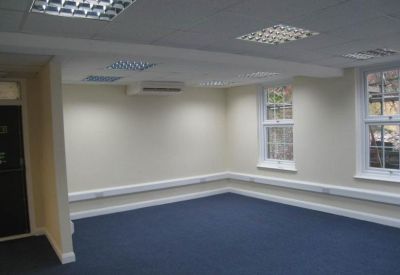 Spacious open-plan office with blue carpeting and white perimeter trunking.