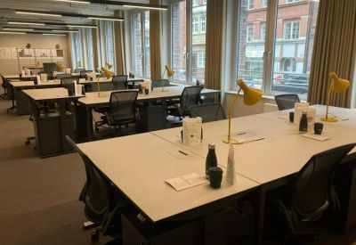 Large open-plan office with rows of desks and yellow task lamps.