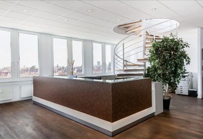 Close-up of a textured dark wood reception desk near large windows and greenery.