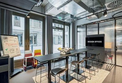 High-top coworking table with bar stools next to a digital display and whiteboard.