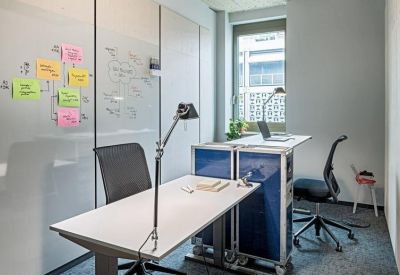 Private two-person office suite with sit-stand desks and a glass partition for notes.