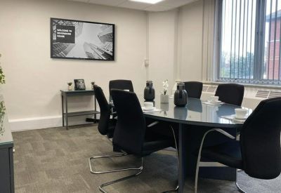 Professional meeting room featuring a glass-top table, black chairs, and a large window.