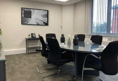 Modern conference room with a circular table, grey carpeting, and monochrome wall art.