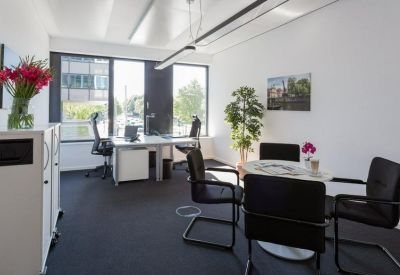 Private office with a circular meeting table, desk, and vibrant flowers.