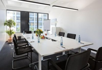 Bright conference room with a large white U-shaped table and city views.