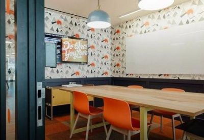 Bright meeting room featuring vibrant patterned wallpaper and orange chairs.