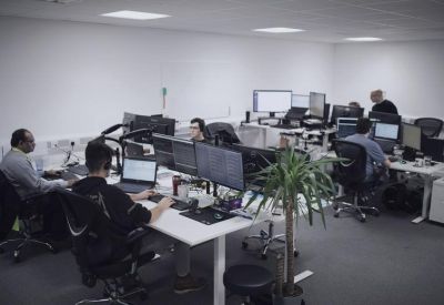 Open-plan office area with modern ergonomic desks and indoor plants.