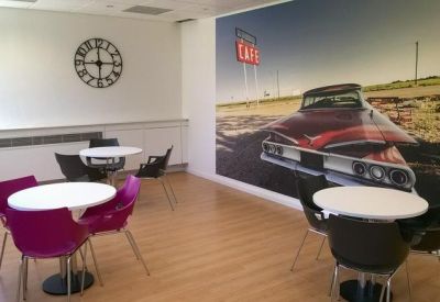 Dining area featuring purple chairs and a large wall mural of a vintage car.