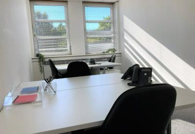 Bright two-person office suite with white desks and natural light.