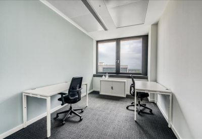 Bright two-person office suite with white desks and black ergonomic chairs.