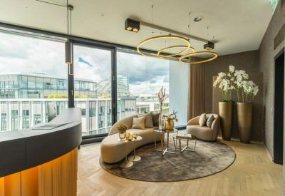 Chic lounge space with a curved beige sofa, round rug, and stylish gold pendant lighting.