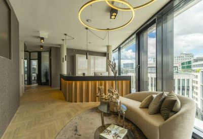 Bright reception area featuring a wood-paneled desk, curved sofa, and large windows with city views.