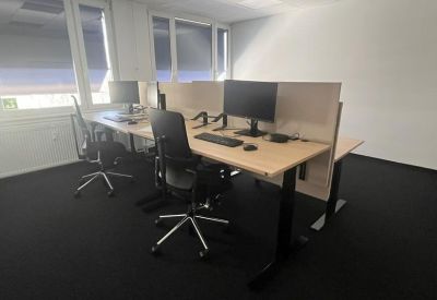 Shared office zone featuring two desks separated by a fabric privacy screen.