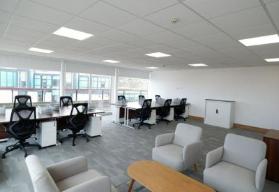 Spacious open-plan workspace with multiple desk banks and soft seating area.