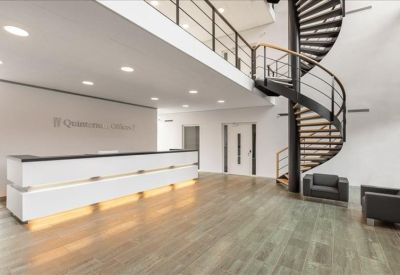 Bright reception area featuring a sleek white front desk and a black spiral staircase.