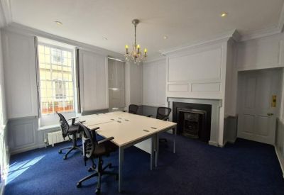 Meeting room with a central desk, ornate chandelier, and classic fireplace.