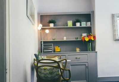 Grey kitchen dresser with decorative plants, flowers, and storage shelves.