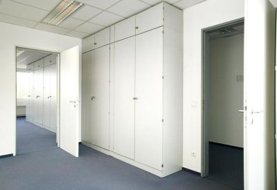 Internal office area featuring floor-to-ceiling white storage cabinets and blue carpet.