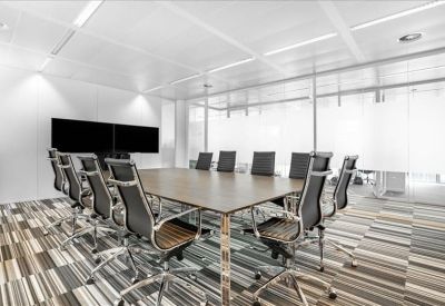 Formal boardroom featuring a long wood-topped table and sleek black chairs.