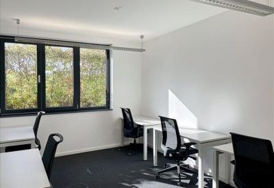 Modern office kitchen with white cabinetry, wooden counters, and a bold red backsplash.