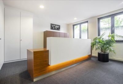 Professional reception desk with a white front and warm wood accents near a large window.