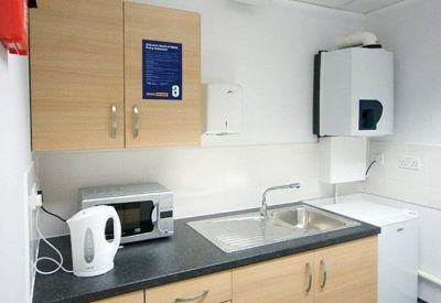 Staff kitchen with wood cabinets, microwave, and sink.