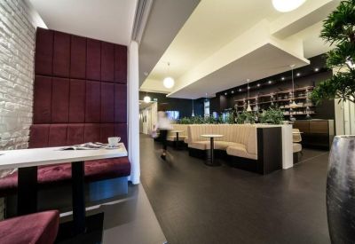 Modern lounge area featuring a plush burgundy wall and white cafe tables.