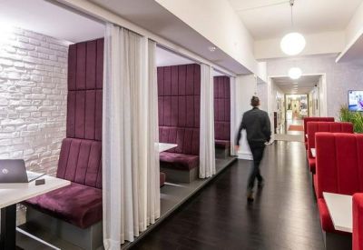 Spacious coworking area with private purple booths and red lounge seating.