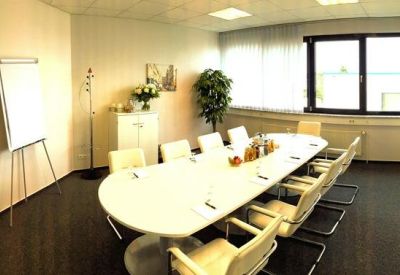 Conference room featuring a white oval table, ergonomic chairs, and a whiteboard.