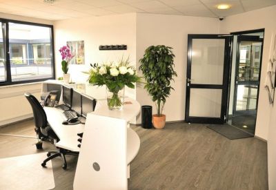 Reception desk with multiple monitors, green plants, and a glass entrance door.