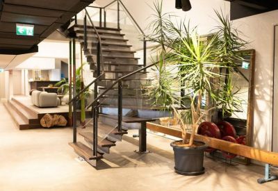 Industrial-style reception area with a metal staircase and large indoor plants.