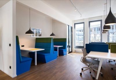 Modern breakout area featuring blue and green privacy booths and white cafe tables.