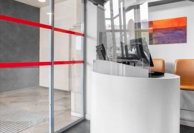 Curved white reception desk with a glass partition and colorful abstract wall art.