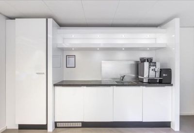 Modern white kitchenette with a coffee machine and built-in storage.