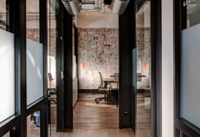 Modern hallway looking into bright glass-walled private office suites.