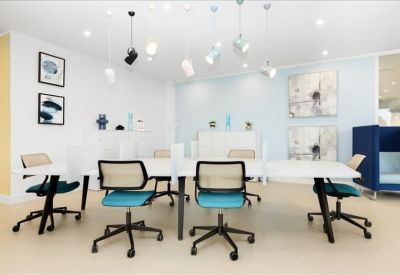 Bright coworking space with teal chairs and unique pendant lighting.