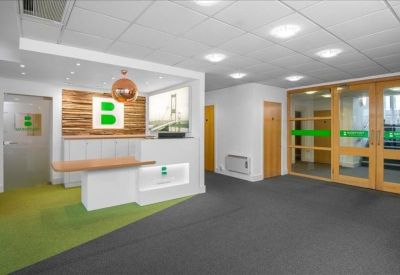 Modern reception area with a white front desk, wooden feature wall, and green branding.